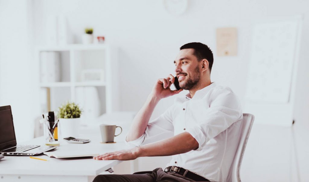 attractive businessman sitting down at desk on phone