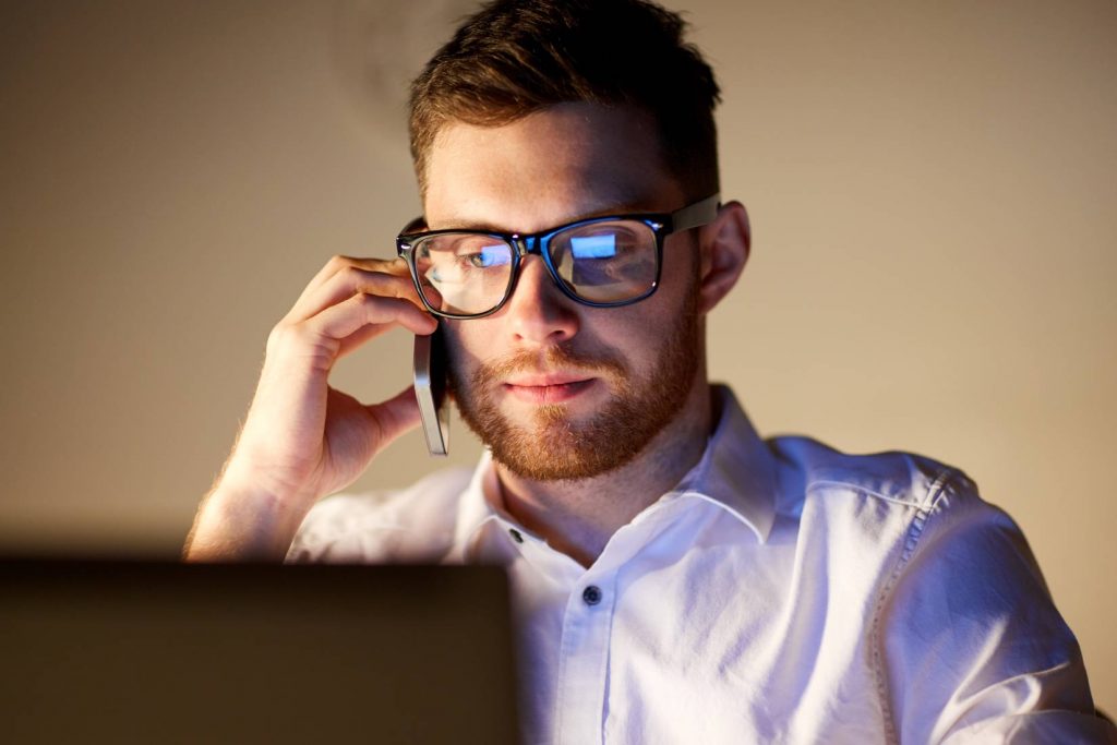 businessman-calling-on-smartphone-at-night-office-PDVQHCJ