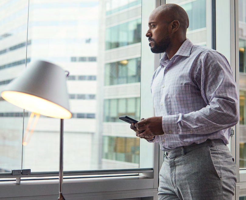 man looking out of window with phone in hand