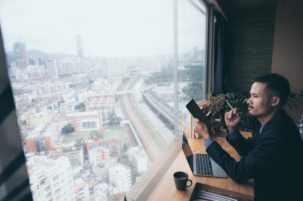 business man with laptop and phone by window